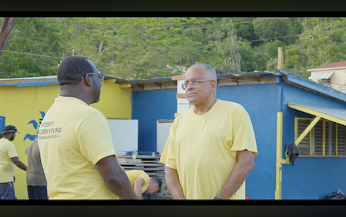 Karl Chambers founder of ICF in yellow shirts conversing amid colorful Jamaican buildings post-Hurricane Melissa – authentic founders story video for non profit footage showcasing origins and impact