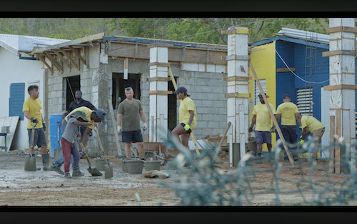 Group of volunteers in yellow shirts mixing and spreading concrete amid damaged structures in Jamaica – compelling fund nonprofit video footage for fundraising and impact storytelling post-Hurricane Melissa