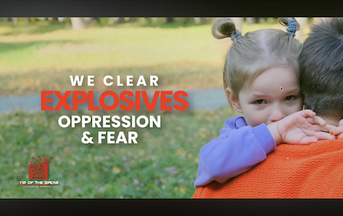 Young child held safely outdoors amid green fields, overlaid with motivational text on clearing fear – heartfelt humanitarian organizations Atlanta video footage from Tip of the Spear Landmine Removal's Ukraine mission