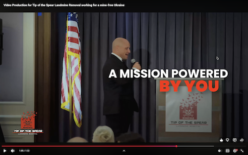 Retired Green Beret Ryan Hendrickson presenting at event with American flag and motivational text overlay in video frame – authentic veteran-led nonprofit video production showcasing landmine removal impact